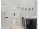 Bright bathroom featuring a tiled shower with modern fixtures, black vanity and door way to bedroom at 14498 Whitewater Way, Brooksville, FL 34604