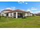 Backyard view of the home featuring a patio and well-manicured lawn at 17222 Holly Well Ave, Wimauma, FL 33598