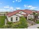 Aerial view of a modern home with red tiled roof, lush landscaping, and double garage at 17222 Holly Well Ave, Wimauma, FL 33598