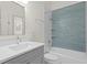 Bright bathroom featuring tub with tiled wall, chrome fixtures, vanity with quartz countertop, and modern fixtures at 18939 Duquesne Dr, Tampa, FL 33647