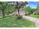 Home exterior featuring a lush green lawn, mature trees, and a concrete driveway leading to an attached garage at 1934 Samantha Ln, Valrico, FL 33594