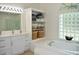 Bright bathroom featuring double sinks, marble countertops, a linen closet and a large soaking tub at 1961 Dunbrody Ct, Dunedin, FL 34698