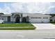 Inviting white home featuring a well-manicured lawn and a three-car garage at 1961 Dunbrody Ct, Dunedin, FL 34698