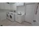 Well-lit laundry room with modern washer, dryer, sink and cabinets at 1961 Dunbrody Ct, Dunedin, FL 34698