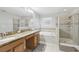 Well lit bathroom showcasing double sinks, granite countertops, soaking tub, and glass enclosed shower at 20102 Oakflower Ave, Tampa, FL 33647