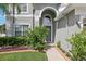 Close-up of a home's front door featuring an arched entryway and lush landscaping at 20102 Oakflower Ave, Tampa, FL 33647