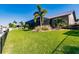 Expansive backyard with lush green grass, palm trees and partial view of the home at 2100 Aqui Esta Dr, Punta Gorda, FL 33950