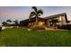Expansive backyard with lush green grass, palm trees and partial view of the home at 2100 Aqui Esta Dr, Punta Gorda, FL 33950