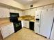 Well-lit kitchen featuring white cabinets, sleek black appliances, and a double-basin sink at 2360 Irish Ln # 16, Clearwater, FL 33763