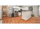 Open kitchen with white cabinets, stainless steel appliances, breakfast bar, and wood flooring at 2604 E Chelsea St, Tampa, FL 33610