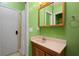 Bathroom features a standard shower with a curtain, wood vanity, framed mirror and bright green walls at 3413 W Kirby St, Tampa, FL 33614