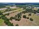 An aerial view of a well-maintained farm property with mature trees, open fields, and distant water features at 3544 Porter Rd, Lithia, FL 33547