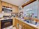 Cozy kitchen featuring laminate countertops, an oven, a microwave, and a stainless steel sink at 3544 Porter Rd, Lithia, FL 33547