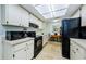 Well-lit kitchen with white cabinets, black appliances, and tile flooring, offering a functional cooking space at 368 Perth Ct # 368, Dunedin, FL 34698
