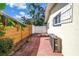 A side yard featuring a brick paved walkway, wooden fence, and a white gate at 3843 Neptune Se Dr, St Petersburg, FL 33705