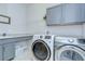 Spacious laundry room with grey cabinets, modern washer and dryer, and sink at 5728 Watercolor Dr, Lithia, FL 33547