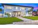Beautiful two-story home with well-manicured lawn, tropical plants and tiled entryway at dusk at 650 70Th Ave, St Pete Beach, FL 33706