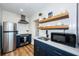 Bright kitchen featuring stainless steel appliances, blue cabinetry, and floating shelves at 650 70Th Ave, St Pete Beach, FL 33706