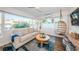 Bright living room featuring a comfortable sofa, a stylish hanging chair, and large windows with scenic views and a ceiling fan at 650 70Th Ave, St Pete Beach, FL 33706