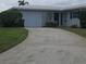 The front of a single-story home with a white roof, a concrete driveway, and a well-maintained lawn at 7303 9Th W Ave # 7303, Bradenton, FL 34209