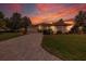 Beautiful single-story home with brick-paved driveway and manicured landscaping under a vibrant sunset sky at 8308 Mobile Cir, Weeki Wachee, FL 34613