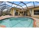 Sparkling pool with screened enclosure, surrounded by brick pavers and outdoor seating area at 8308 Mobile Cir, Weeki Wachee, FL 34613