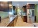 Galley kitchen boasts stainless steel appliances, granite counters, dark cabinets, and adjacent laundry area at 8722 Thornwood Ln, Tampa, FL 33615