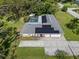 Aerial view of a single-story home with a gray roof, pool, solar panels, and a large concrete driveway at 903 Tomahawk Trl, Brandon, FL 33511