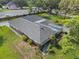 Aerial view showcasing a home with a screened-in pool and shingled roof surrounded by lush greenery at 903 Tomahawk Trl, Brandon, FL 33511