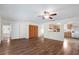 Living area with wood floors, ceiling fan and kitchen view through wall cut-out at 903 Tomahawk Trl, Brandon, FL 33511