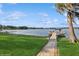 Waterfront backyard featuring a well-manicured lawn, mature tree, and walkway leading to a private dock at 919 Ballinger Rd, Lutz, FL 33548