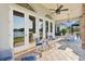 Inviting covered patio featuring tile flooring, ceiling fans and white rocking chairs overlooking a tranquil lake view at 919 Ballinger Rd, Lutz, FL 33548