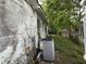 Shows the exterior of a distressed property with an AC unit and overgrown vines at 9606 N Newport Ave, Tampa, FL 33612