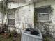 Shows the exterior of a distressed property with an AC unit and overgrown vines at 9606 N Newport Ave, Tampa, FL 33612