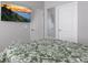 Comfortable bedroom featuring a green floral comforter, a wall-mounted TV, and closet doors at 10153 Spruce River Way, Parrish, FL 34219