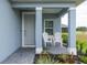 Charming front porch with two white chairs, a gray door, and colorful landscaping at 10153 Spruce River Way, Parrish, FL 34219