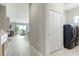 Hallway leading to the living area and featuring a laundry closet with a modern washer and dryer at 10153 Spruce River Way, Parrish, FL 34219