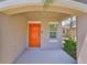 Inviting covered entry featuring a bright orange front door and charming architectural details at 10210 White Linen Ave, Riverview, FL 33578