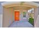 Covered front entry featuring vibrant orange door and neutral-toned exterior at 10210 White Linen Ave, Riverview, FL 33578