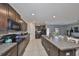 Modern kitchen with dark wood cabinets, granite counters, and stainless-steel appliances open to living room at 10210 White Linen Ave, Riverview, FL 33578