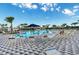 Relaxing community pool area with lounge chairs, tables, umbrellas, and clear blue water at 10732 Chippewa Dr, Parrish, FL 34219