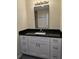 Modern bathroom vanity with white shaker cabinets, black granite countertop, and oversized mirror at 1107 Howard St, Clearwater, FL 33756