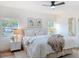 Bright bedroom featuring a ceiling fan, stylish decor, two windows, and a comfortable bed with textured throw at 1267 Woodlawn Ter, Clearwater, FL 33755