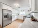 Bright kitchen featuring stainless steel appliances, white cabinets and light wood flooring and marble countertops at 1267 Woodlawn Ter, Clearwater, FL 33755