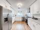 Bright kitchen featuring stainless steel appliances, white cabinets and light wood flooring at 1267 Woodlawn Ter, Clearwater, FL 33755