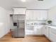 Bright kitchen showcasing stainless steel refrigerator and ample white cabinetry storage at 1267 Woodlawn Ter, Clearwater, FL 33755