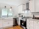 Well-lit kitchen featuring a farmhouse sink, stainless steel appliances, and white cabinetry at 1267 Woodlawn Ter, Clearwater, FL 33755