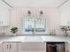 Sunlit kitchen area featuring a farmhouse sink, stainless steel appliances, and white cabinets at 1267 Woodlawn Ter, Clearwater, FL 33755