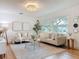 Bright living room with hardwood floors, stylish sofas, modern lighting, and large windows overlooking greenery at 1267 Woodlawn Ter, Clearwater, FL 33755