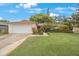 Charming single-story home featuring a well-manicured lawn, two-car garage and vibrant landscaping at 13563 Cordova Dr, Largo, FL 33774